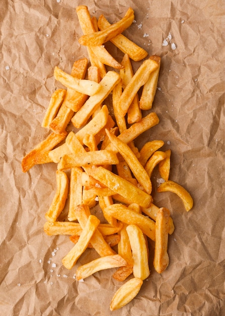 Top view of french fries with salt on paper