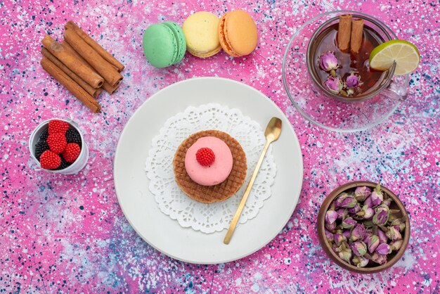 Top view french macarons with cinnamon berries and tea on the colorful background cake biscuit sugar sweet color bake