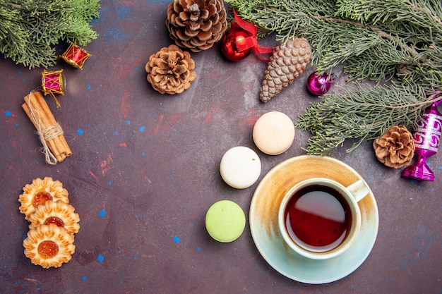 Top view of french macarons with cookies and tea on black