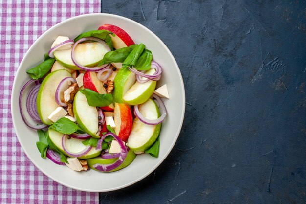 Top view fresh apple salad in bowl purple and white checkered tablecloth on dark table free space