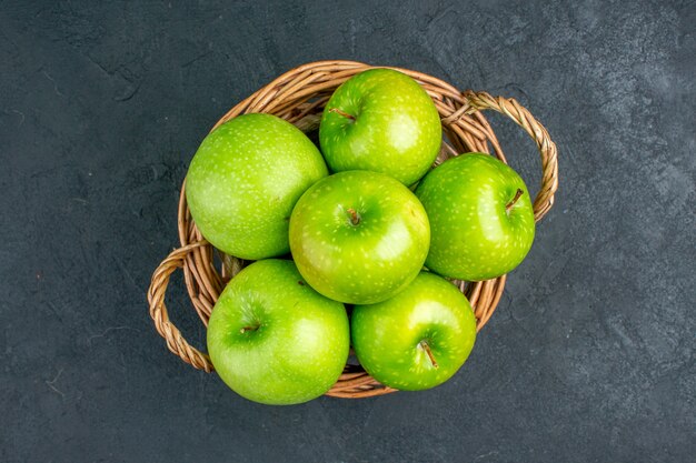 Top view fresh apples in wicker basket on dark surface free space