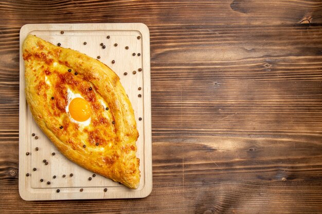 Top view fresh baked bread with cooked egg on brown desk dough breakfast egg bun food