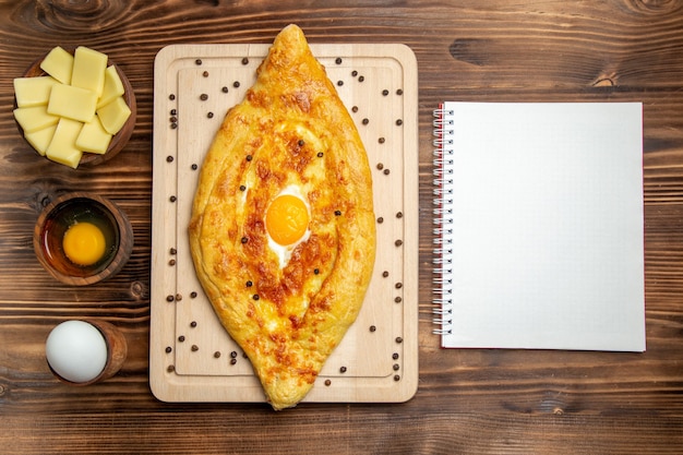 Free photo top view fresh baked bread with cooked egg on brown desk dough food breakfast bake bun meal egg