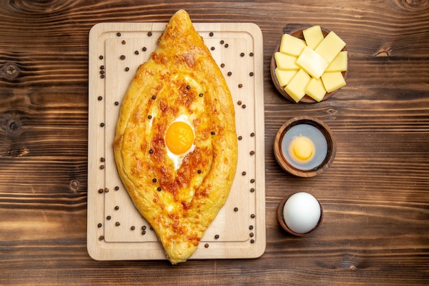 Free photo top view fresh baked bread with cooked egg on a brown desk dough food breakfast bake bun meal