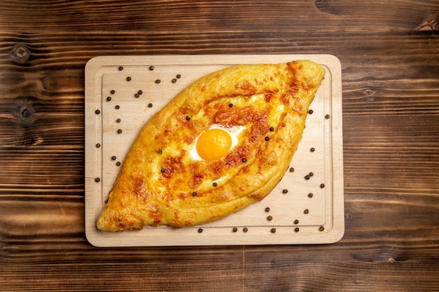 Top view fresh baked bread with cooked egg on brown wooden desk dough bun breakfast eggs food