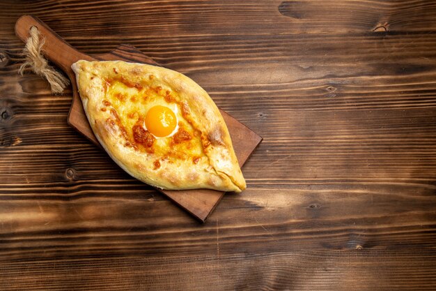 Top view fresh baked bread with cooked egg on wooden surface bread dough bun food breakfast