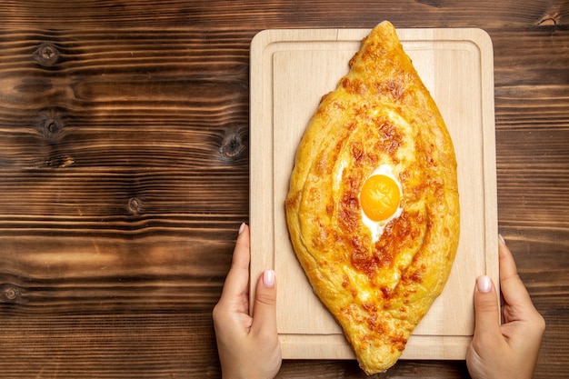 Top view fresh baked bread with cooked egg on wooden surface bread dough meal bun food breakfast egg