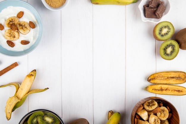 Top view of fresh banana and kiwi fruits arranged on white with copy space