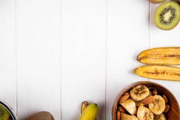 Top view of fresh banana and kiwi fruits on white wood with copy space