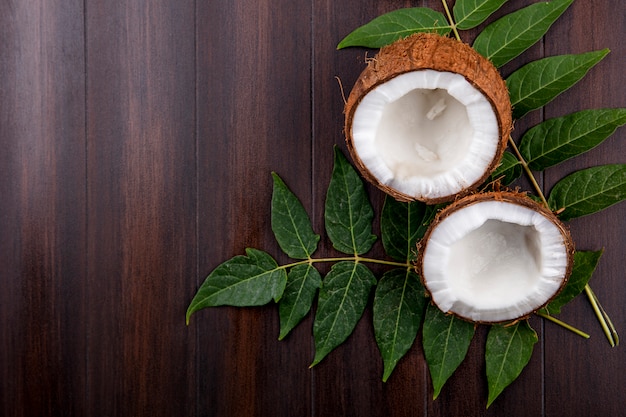 Top view of fresh and brown coconuts with leaves on wood