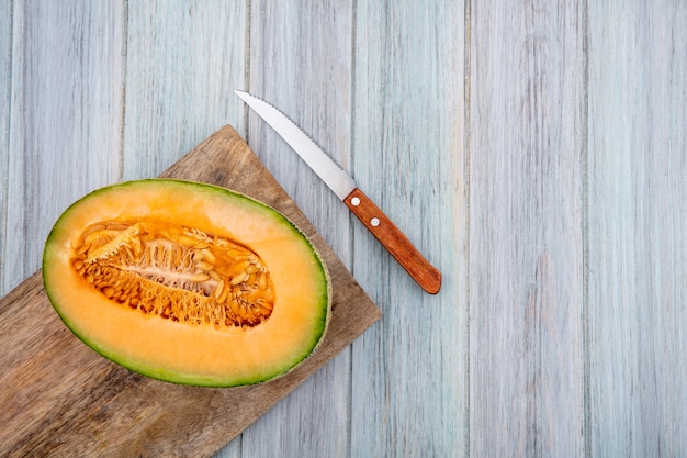 Free Photo top view fresh cantaloupe melon on wooden kitchen board with knife on grey wood with copy space