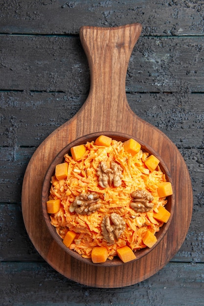 Top view fresh carrot salad grated salad with walnuts on a dark desk diet salad color nut health