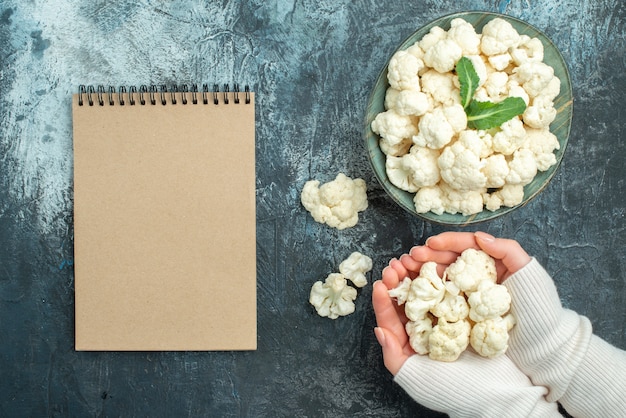 Free photo top view fresh cauliflower inside plate and in female hands on light-grey table