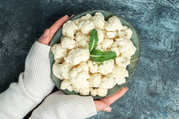 Free Photo top view fresh cauliflower inside plate in female hands on light-grey table