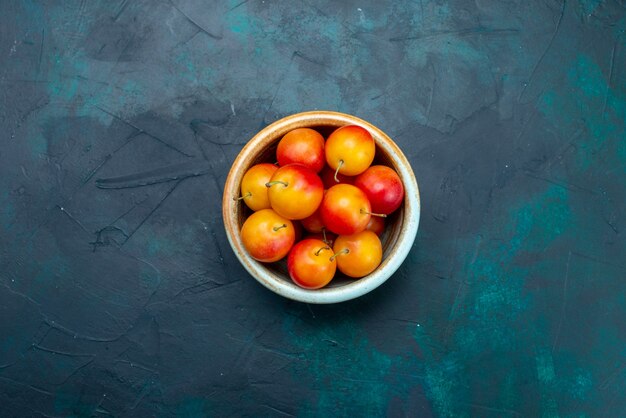 Top view fresh cherry-plums sour and mellow fruits inside little pot on the dark-blue background fruit mellow fresh vitamine