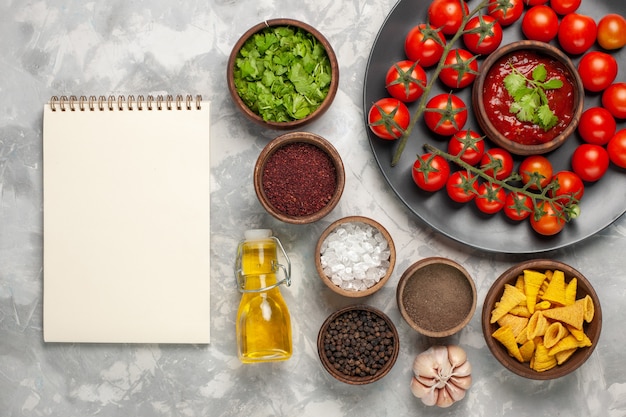 Free photo top view fresh cherry tomatoes inside plate with different seasonings and oil on white surface