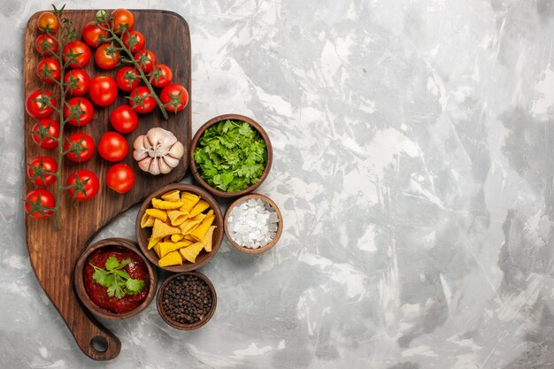 Top view fresh cherry tomatoes with different seasonings and greens on white surface