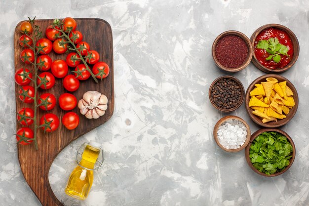 Top view fresh cherry tomatoes with different seasonings on white surface