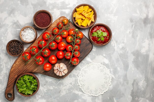 Top view fresh cherry tomatoes with seasonings and greens on white surface