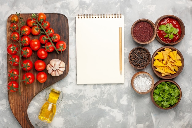 Free photo top view fresh cherry tomatoes with seasonings and notepad on white surface