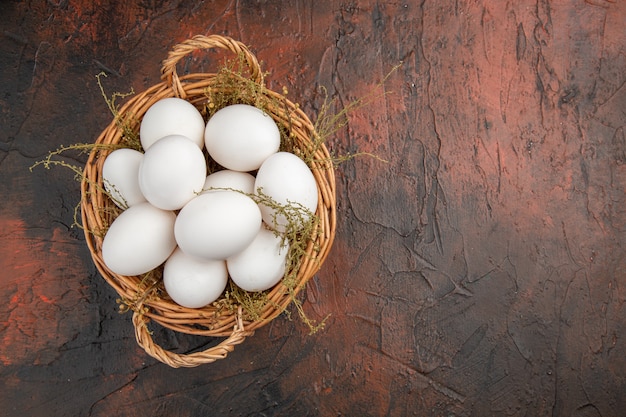 Top view fresh chicken eggs inside basket on dark table