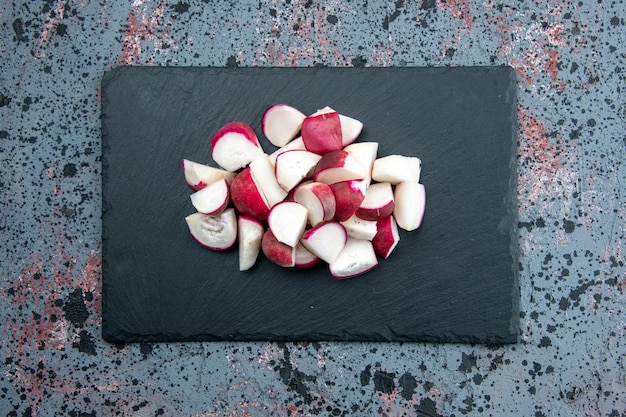 Free Photo top view of fresh chopped radishes on dark color cutting board on mixed colors background