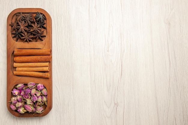 Top view fresh cinnamon with flowers on white desk flower plant color wood