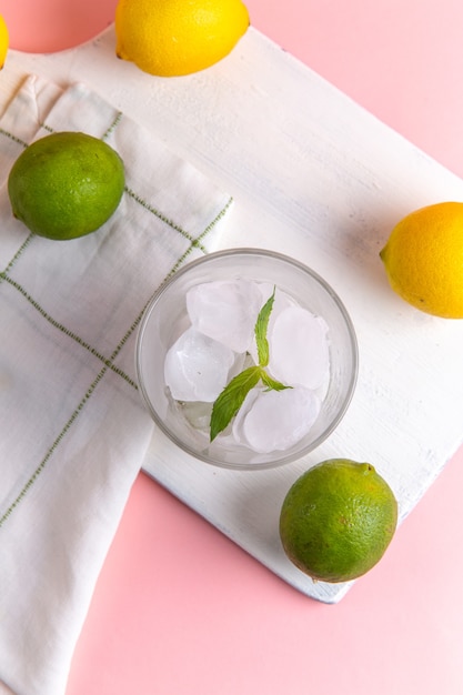 Free photo top view of fresh cold lemonade with ice along with fresh lemons on the pink surface