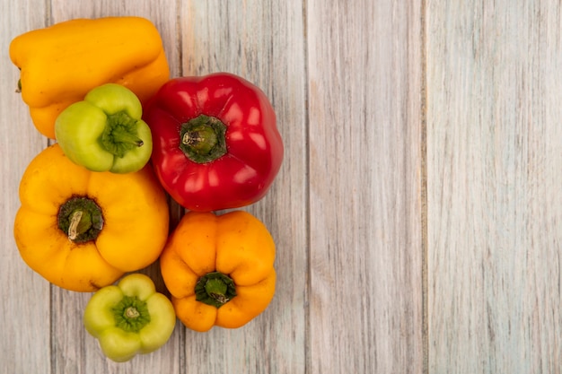 Top view of fresh colorful bell peppers isolated on a grey wooden surface with copy space