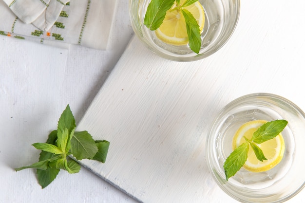 Free photo top view of fresh cool lemonade with sliced lemons inside glasses on light-white surface