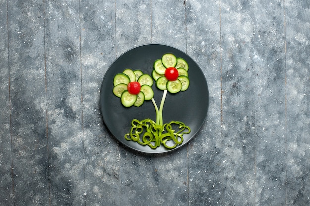 Top view fresh cucumbers flower designed salad on a grey space