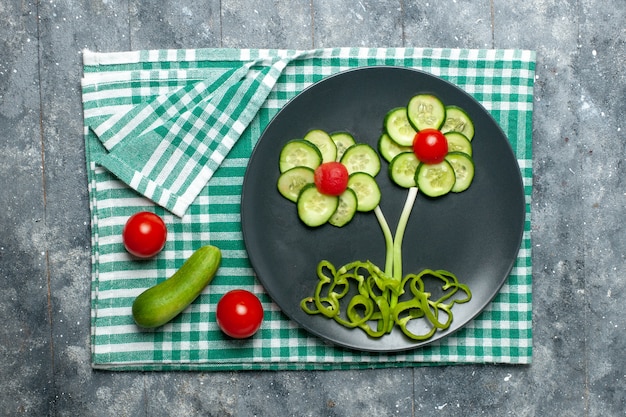 Free photo top view fresh cucumbers flower designed salad on grey space