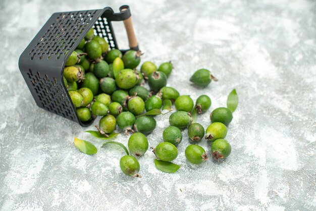 Top view fresh feykhoas scattered from basket on grey isolated surface