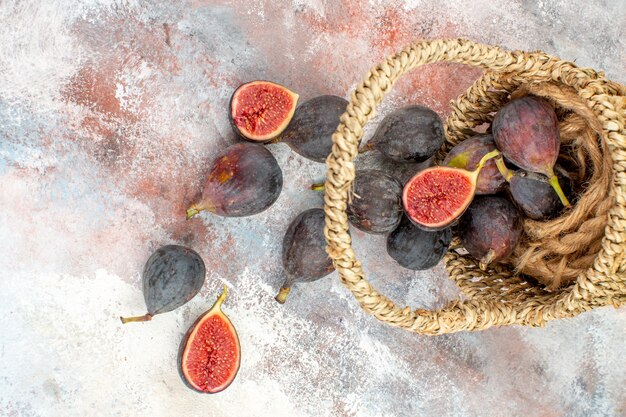 Top view fresh figs scattered from basket on nude background