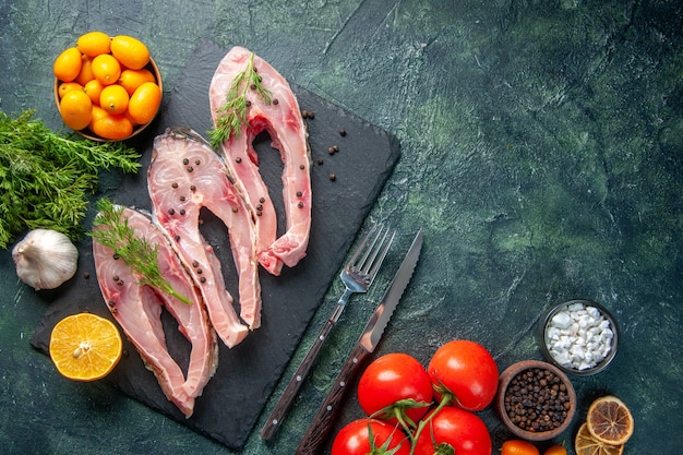 top view fresh fish slices with greens red tomatoes and kumquats on dark background