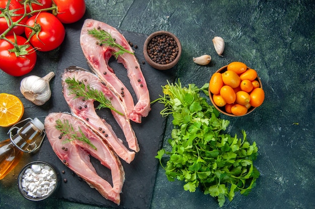 top view fresh fish slices with red tomatoes and greens on dark background