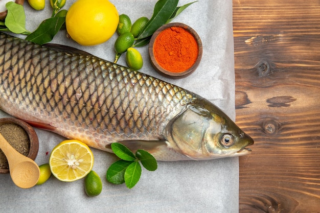 Top view fresh fish with lemons on a brown desk