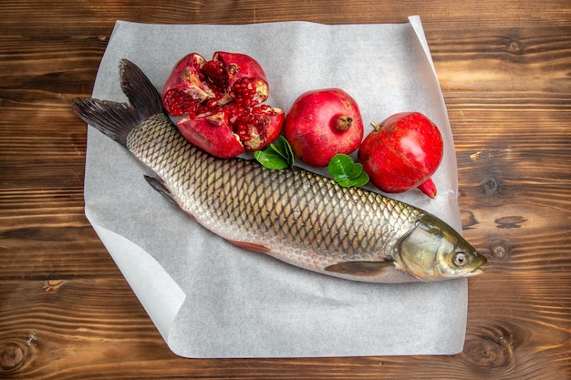 Top view fresh fish with pomegranates on wooden desk