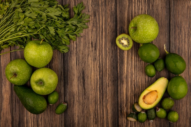 Top view of fresh food such as green apples limes feijoas avocados and parsley isolated on a wooden wall with copy space