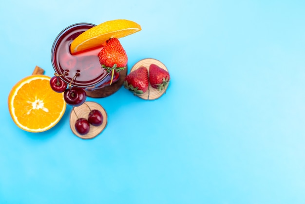 A top view fresh fruit cocktail with fresh fruit slices ice cooling on blue, drink juice cocktail fruit color