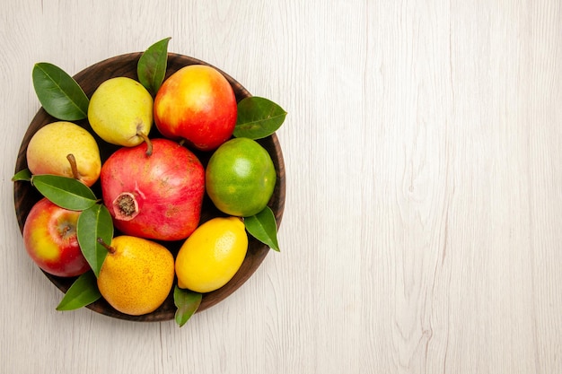 Top view fresh fruits apples pears and other fruits inside plate on a white desk fruits ripe tree color mellow many fresh