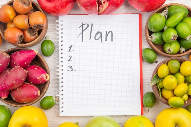 Top view fresh fruits composition different fruits with plan written notepad on white background