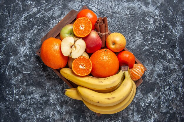 Top view fresh fruits cut fruits and cinnamon sticks on wooden tray on table