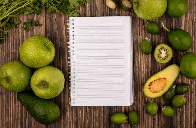 Top view of fresh fruits such as green apples limes feijoas avocados and parsley isolated on a wooden surface with copy space