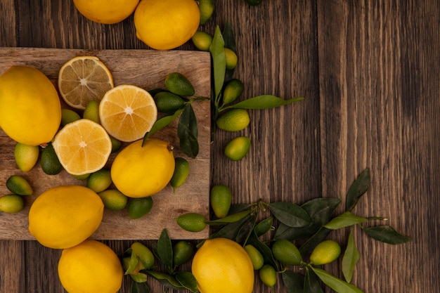 Top view of fresh fruits such as kinkans and lemons isolated on a wooden kitchen board on a wooden wall with copy space