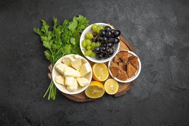 Top view fresh grapes with white cheese greens and lemon slices on a dark surface meal fruit milk food