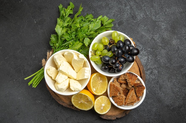 Top view fresh grapes with white cheese greens and lemon slices on dark surface meal fruit milk food