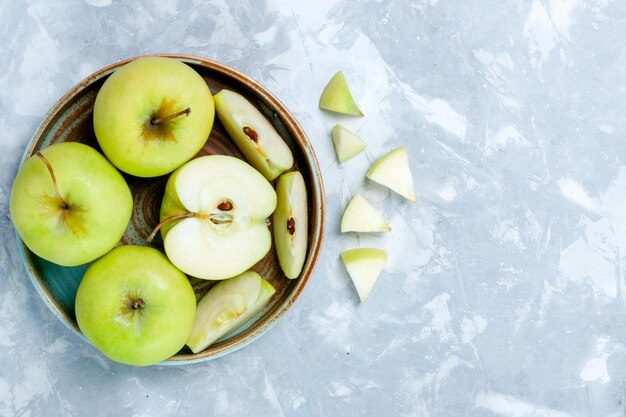 Top view fresh green apples sliced and whole fruits on light-white surface