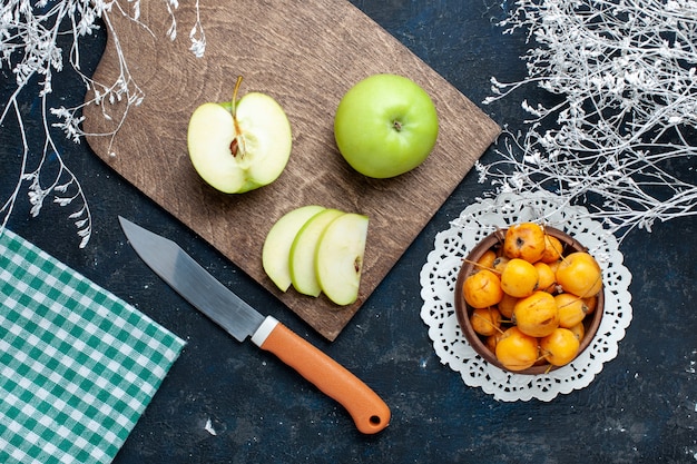 Top view of fresh green apples with sweet mellow cherries on dark-blue desk, fresh mellow food vitamine