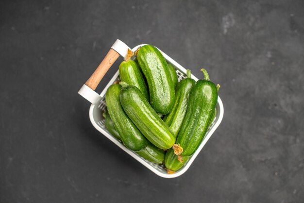 Top view fresh green cucumbers inside basket on dark background